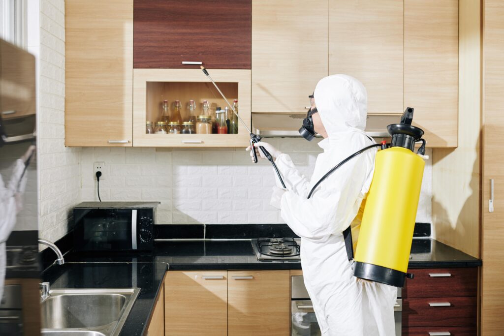worker-in-hazmat-suit-applying-spray-on-surfaces