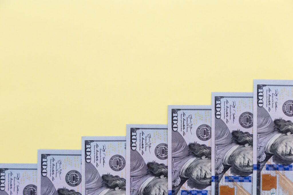 Hndred-dollar-bill-notes-increasing-in-size-like-steps-on-yellow-background